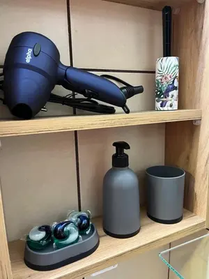 a shelf with a hair dryer and a bottle on it at Sailboat Apartment in Niš