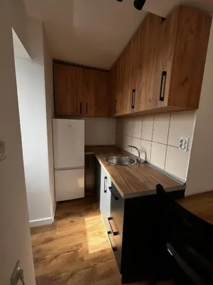 a small kitchen with wooden cabinets and a sink at Sailboat Apartment in Niš