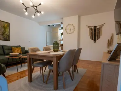 a dining room and living room with a table and chairs at Apartman Nest in Vranje