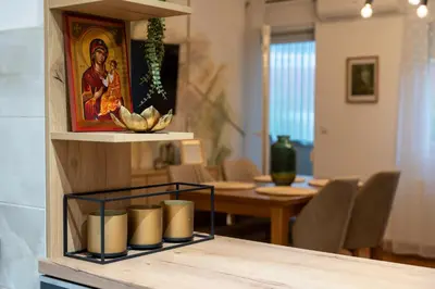 a table with a shelf with candles and a painting at Apartman Nest in Vranje