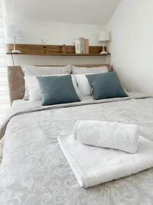 a large white bed with blue pillows on it at La Perla Apartman in Vrnjačka Banja