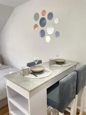 a white table with two plates and glasses on it at La Perla Apartman in Vrnjačka Banja