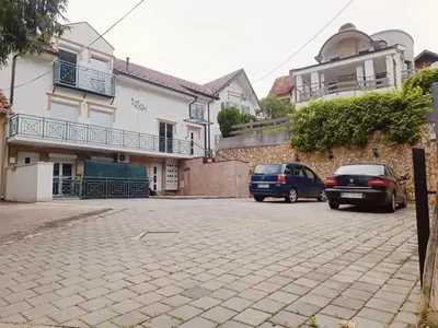 two cars parked in a parking lot in front of a house at La Perla Apartman in Vrnjačka Banja