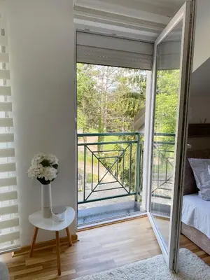 a bedroom with a sliding glass door leading to a balcony at La Perla Apartman in Vrnjačka Banja