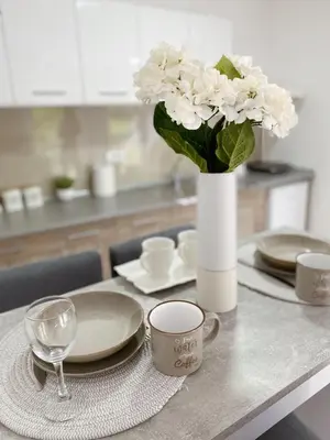a table with a vase with white flowers on it at La Perla Apartman in Vrnjačka Banja