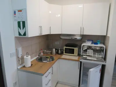 a kitchen with white cabinets and a sink and a microwave at Aqua Lux Apartman in Jagodina
