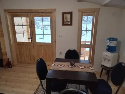 a dining room with a table and chairs and a door at Milica 2 Mezdrejska 87 A in Crni Vrh