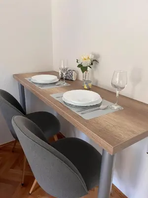 a wooden table with two chairs and a table with wine glasses at Apartman Polo in Jagodina