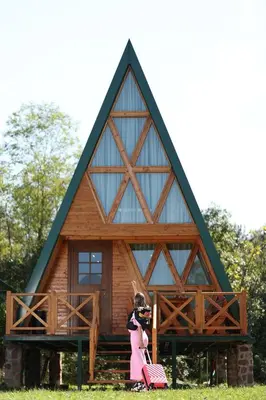 a little girl standing in front of a cabin at Magareće Mleko Eko Farma Sisevac Wellness&Spa in Paraćin