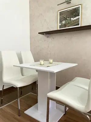 a white table and chairs with two candles on it at Apartman IN in Vrnjačka Banja