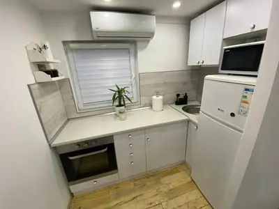 a small kitchen with white cabinets and a sink at Queen Apartmančić in Zaječar