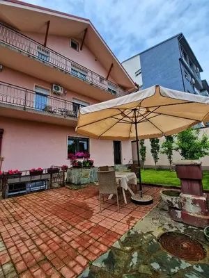 a patio with a table and an umbrella in front of a building at Apartman Cvetkovic in Vranje