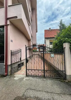 a black gate in front of a pink building at Apartman Cvetkovic in Vranje
