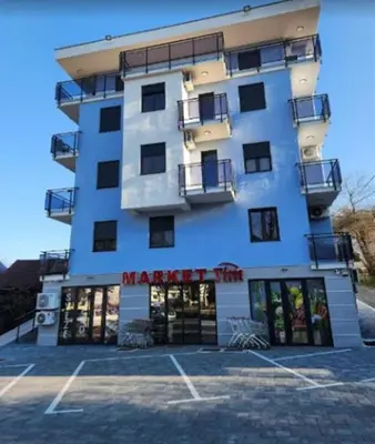 a large white building with a parking lot in front of it at Apartman Imperator Vrnjačka Banja in Vrnjačka Banja