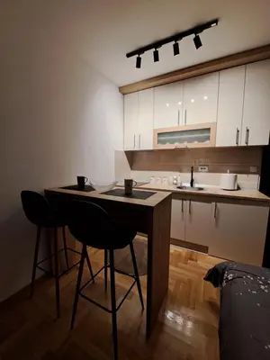 a kitchen with a table and two bar stools at Apartman Imperator Vrnjačka Banja in Vrnjačka Banja