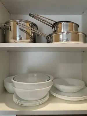 a kitchen with white bowls and a pot on shelves at Apartman Sunce in Vrnjačka Banja