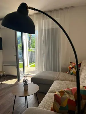 a large black lamp in a living room with a couch at Apartman Sunce in Vrnjačka Banja