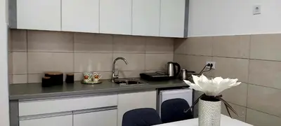 a kitchen with white cabinets and a table with a vase of flowers at RELAX LUX AKVA PARK 2(K-KOMPLEX) in Jagodina