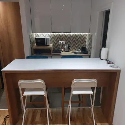 a kitchen with a counter with two white stools at Centar Crnjanski in Jagodina