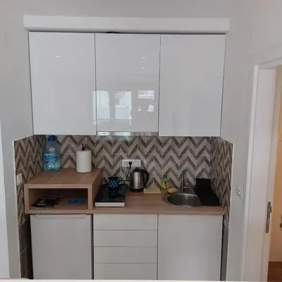 a small kitchen with white cabinets and a sink at Centar Crnjanski in Jagodina