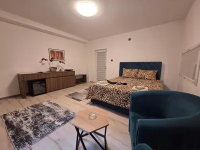 a bedroom with a bed and a blue chair at Apartmani relax in Leskovac