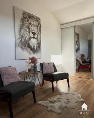 a living room with two chairs and a painting of a lion at House Inn in Pirot
