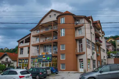 a tall building with cars parked in front of it at Apartmani Vrla in Vladičin Han