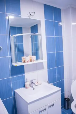 a blue tiled bathroom with a sink and a mirror at Apartmani Vrla in Vladičin Han
