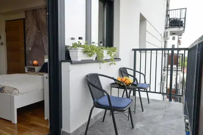 a balcony with two chairs and a table with fruit on it at Apartman Luxor in Jagodina