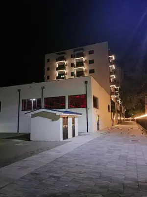 a large white building with a parking lot at night at Apartman Luxor in Jagodina