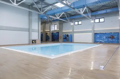 a large swimming pool in a room with a wooden floor at Apartman Luxor in Jagodina