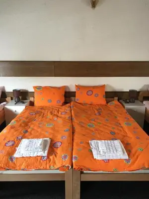a bed with an orange comforter and two towels at Prenoćiste Živković in Pirot