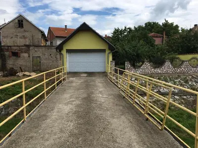 a driveway leading to a garage with a yellow house at Prenoćiste Živković in Pirot