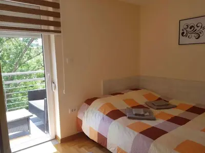 a bedroom with a bed and a sliding glass door at Perla Lux in Vrnjačka Banja