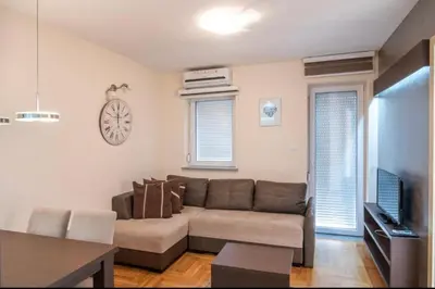 a living room with a couch and a clock on the wall at Perla Lux in Vrnjačka Banja