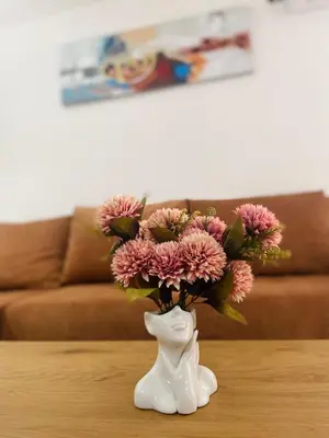 a white vase with pink flowers in it on a table at Urban Chic Studio in Niš
