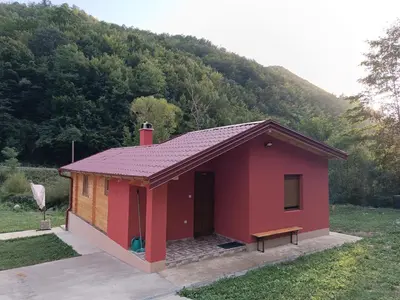 a small red building with a hill in the background at Milica 1 Mezdrejska 87 in Kalna