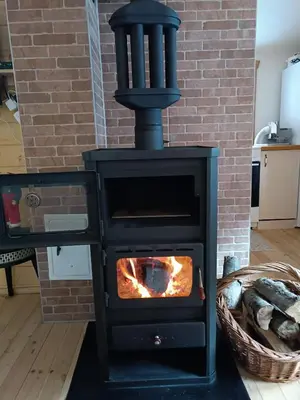 a black stove in a room with a brick wall at Milica 1 Mezdrejska 87 in Kalna
