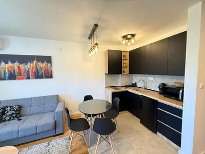 a kitchen and living room with a blue couch and a table at Kovan Lux 9 Sokobanja in Soko Banja