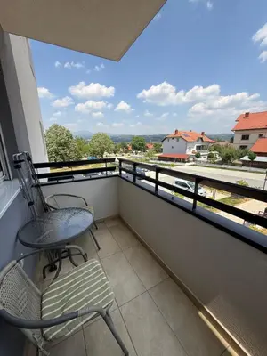 a balcony with a chair and a view of a building at Kovan Lux 11 Sokobanja in Soko Banja