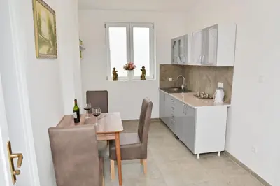 a kitchen with a table and chairs and a kitchen with white cabinets at Apartmani Homoljsko Jutro ☆☆☆☆ Apartments Homolje Morning ☆☆☆☆ in Žagubica