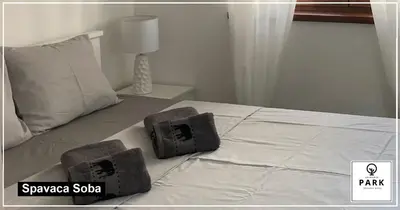 a white bed with two boxes on top of it at Apartman Park Promenada in Vrnjačka Banja
