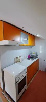 a kitchen with orange cabinets and a white stove top oven at Apartman Jova in Vrnjačka Banja
