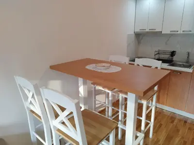 a kitchen with a wooden table and white chairs at Apartman Andjelika Vrnjacka Banja in Vrnjačka Banja