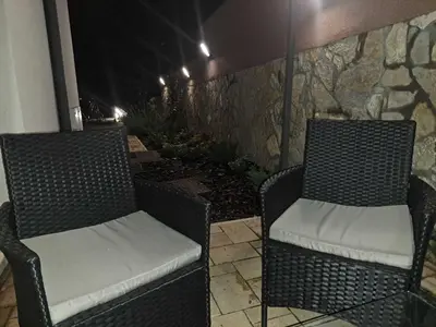 two wicker chairs sitting on a patio at night at D&M Porodični apartman in Vrnjačka Banja