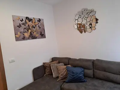a couch in a living room with two pictures on the wall at D&M Porodični apartman in Vrnjačka Banja