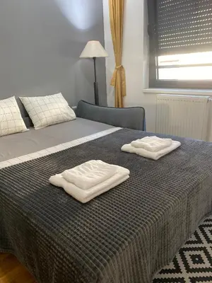 a bed with two white towels on top of it at Family Home Niš , FREE parking in Niš
