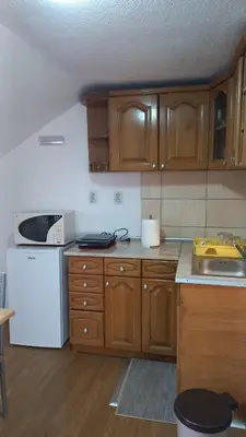 a kitchen with wooden cabinets and a white refrigerator at Apartman Saša in Vranje