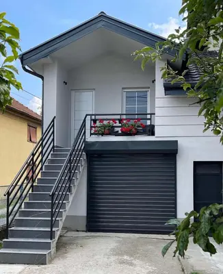 a white house with a garage door and some stairs at Aqua Casa in Vrnjačka Banja