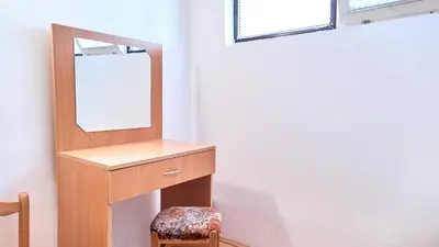 a dressing table with a mirror and a stool at Janković Apartmani u centru in Soko Banja